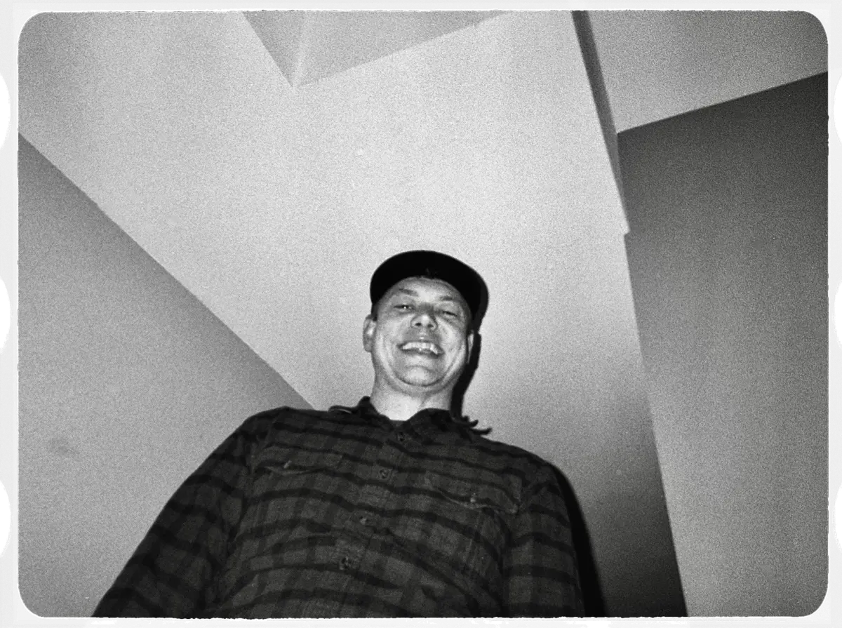 low quality black and image film image of a smiling man in plaid