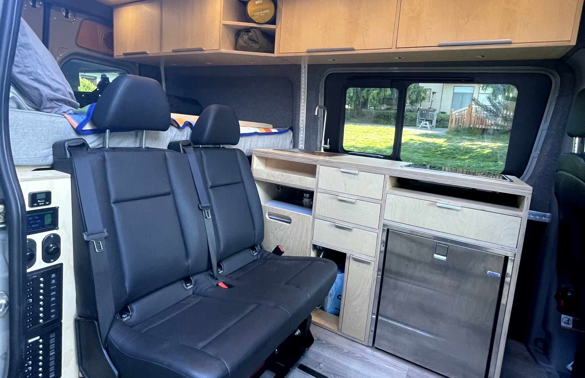 image of the interior of the van showing the modified seat, custom cabinetry, refrigerator and lighting