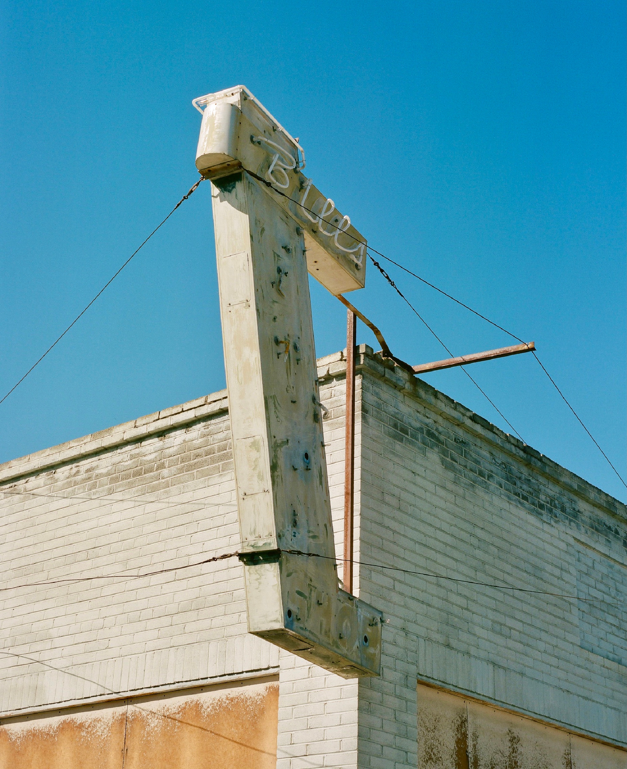 blue sky behind a dilapidated structure with an unlit neon sign that says bills