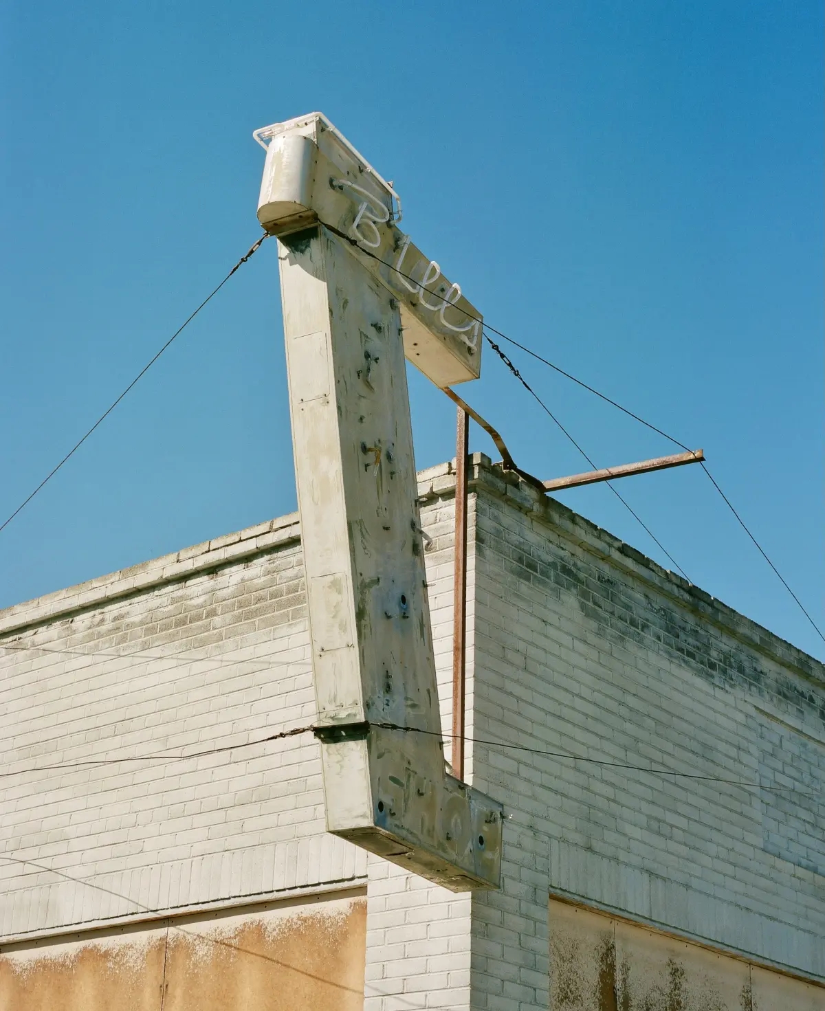 blue sky behind a dilapidated structure with an unlit neon sign that says bills