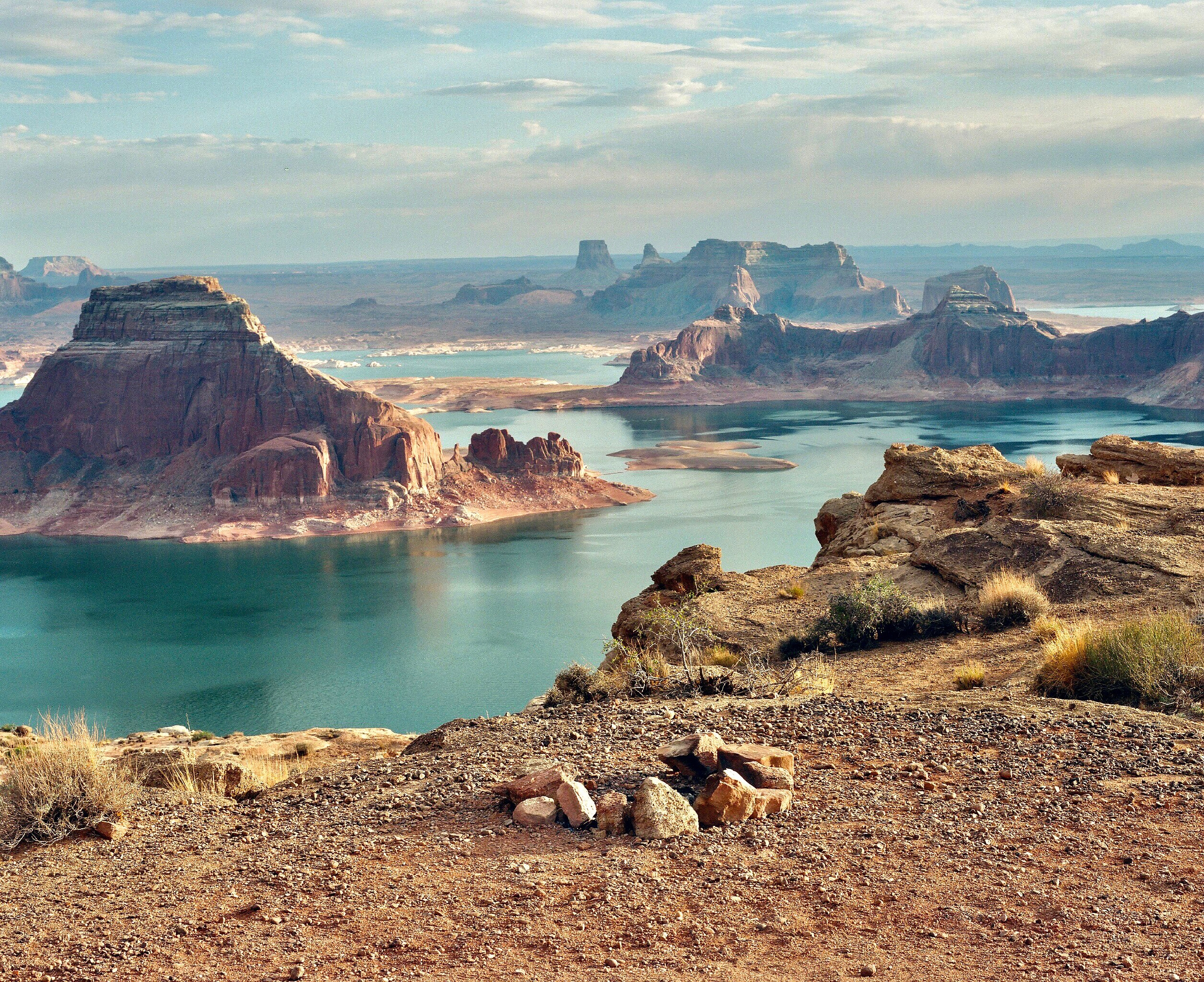 Lake Powell with low water level, surrounded by high gradient canyon cliffs, bright blue water, near sunset