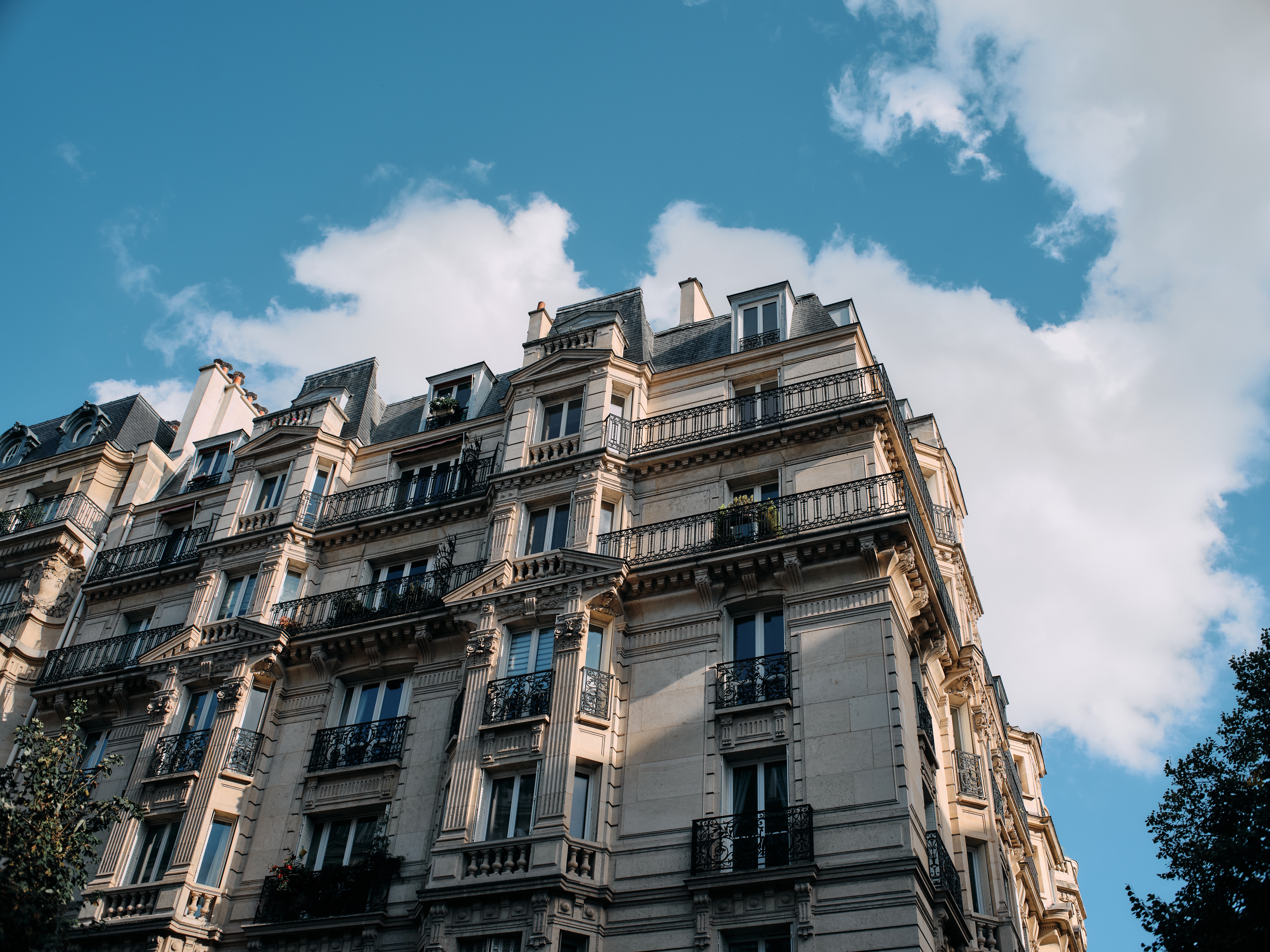 sun rays and long shadows on an apartment building in paris with cloudy blue skys behind