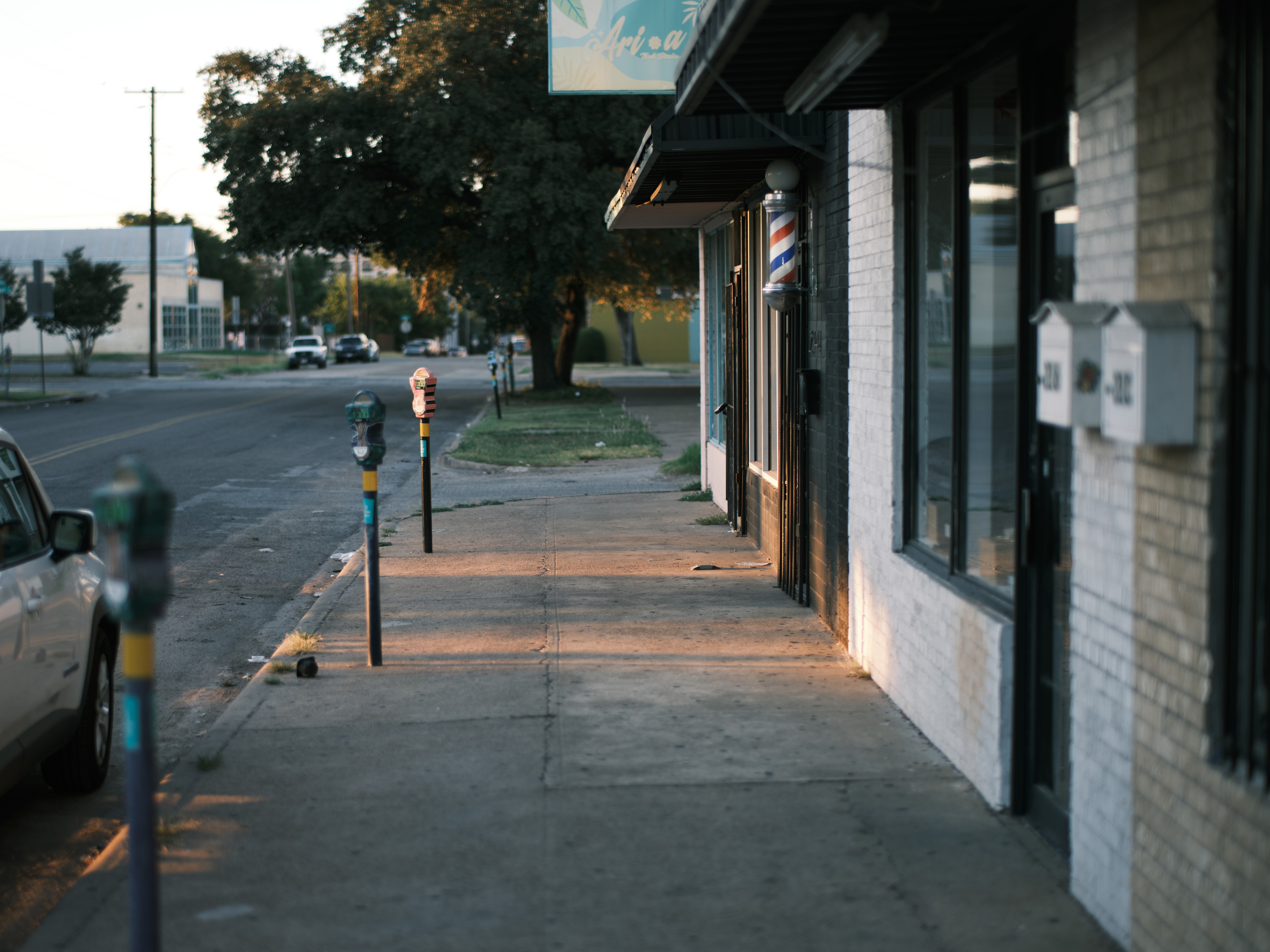 single parking meter in focus looking down a vacant street in the dying light of a texas summer sunset