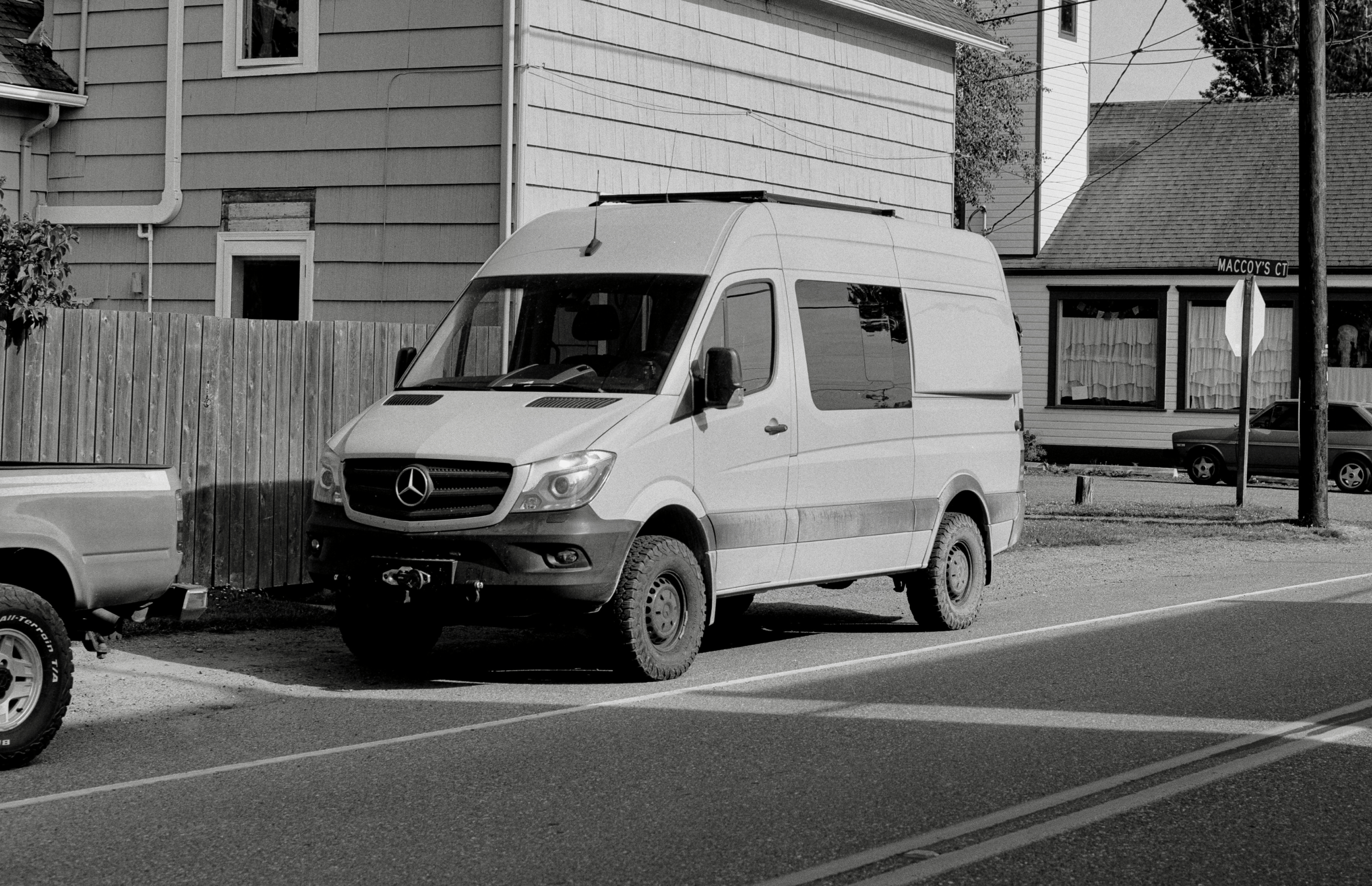 black and white image of a large campervan on a quiet rural street