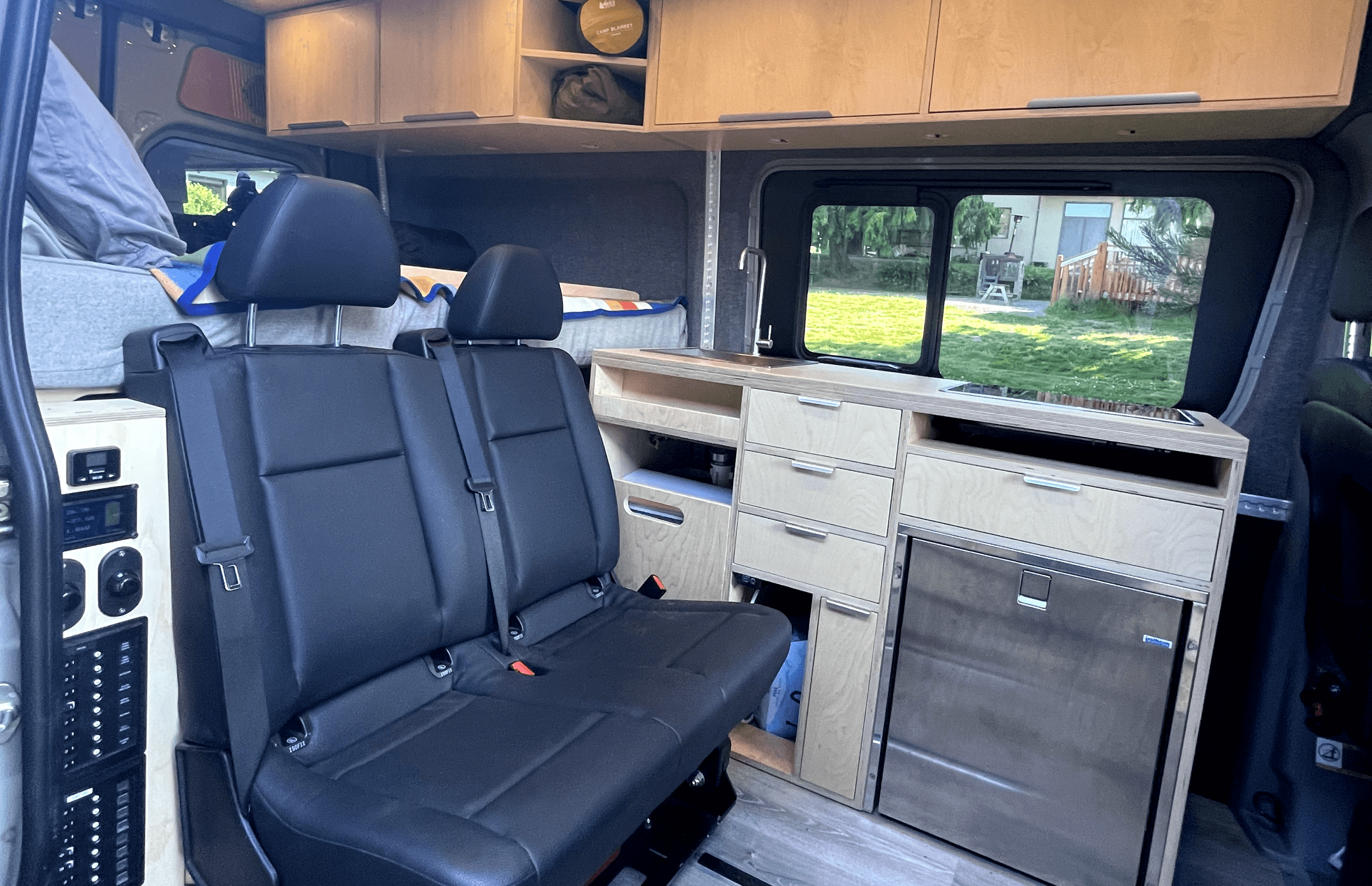 image of the interior of the van showing the modified seat, custom cabinetry, refrigerator and lighting